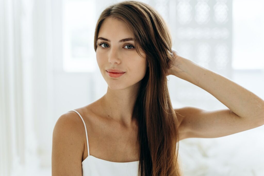 Portrait of adorable woman with healthy skin sitting in front of the camera with calm expression